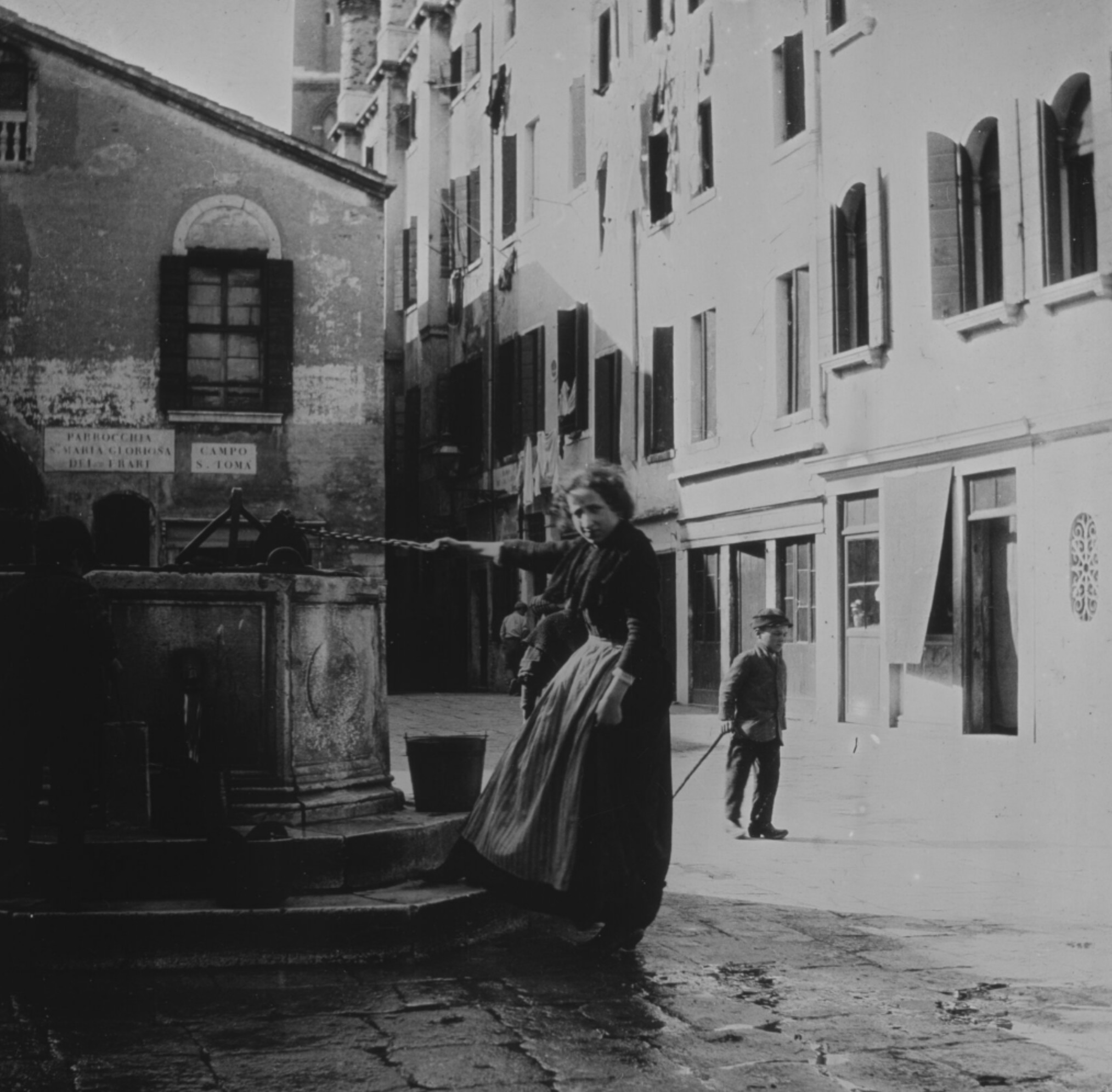 Frau holt Wasser aus einem Brunnen.